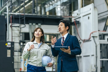 工場を視察する男性ビジネスパーソンと女性作業員