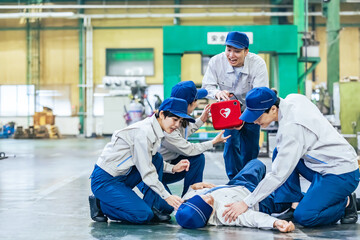 工場で倒れた作業員をAEDで救護するグループ