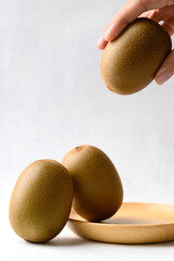 Fresh kiwi fruit with wooden plate and hand on white background, Healthy eating