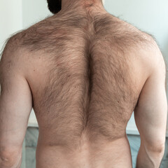 Bearded man seen from behind, showing unshaved neck and tied back hair.  masculinity, grooming or...