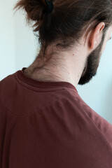 Bearded man seen from behind, showing unshaved neck and tied back hair.  masculinity, grooming or...