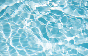 Blue water with ripples on the surface. Defocus blurred transparent blue colored clear calm water surface texture with splashes and bubbles. Water waves with shining pattern texture background.