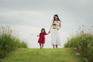 happy mother walking with her toddler girl on grass field