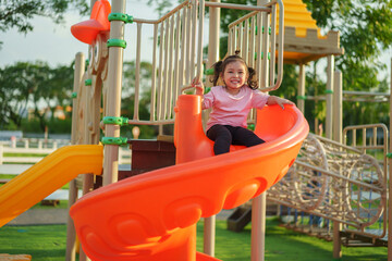 happy toddler baby girl sliding and playing at playground