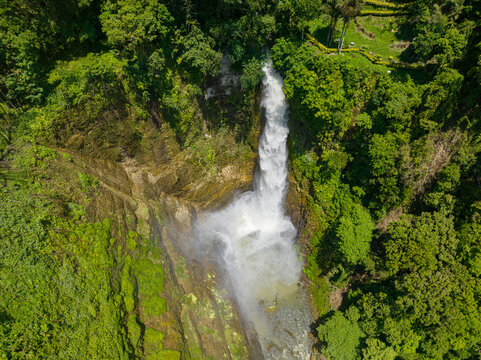 Mist from water splash of Hikong Bente Waterfall surrounded by mountain jungle, rainforest and green trees. Lake Sebu. Mindanao, Philippines.