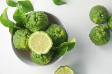 Fototapeta premium Kaffir lime or bergamot fruit, Kaffir lime or citrus hystrix fruit sliced and decorated with leaves on a white background