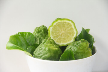 Kaffir lime or bergamot fruit, Kaffir lime or citrus hystrix fruit sliced and decorated with leaves on a white background
