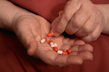 Elderly woman holding pill drug in hand. Healthy medical concept. Close up mature woman taking pills. Colorful pills in old woman hand.