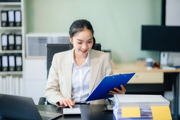 Asian woman talking on the phone with a customer Young positive female accountant using smartphone talking