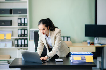 Asian woman talking on the phone with a customer Young positive female accountant using smartphone talking
