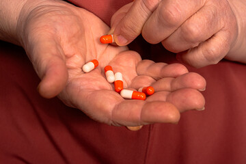 Old woman holding pills in hand. Healthy medical concept. Close up mature woman taking pills. Colorful pills in old woman hand.