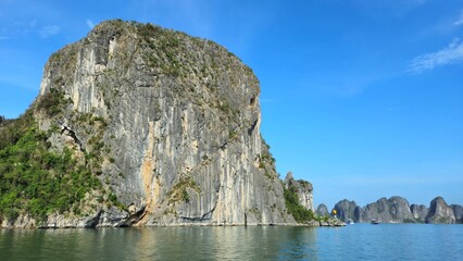 Naklejka premium Limestone rock islands in Ha Long bay, Vietnam. The cliff is composed of steep, rugged limestone formations, with vertical striations.