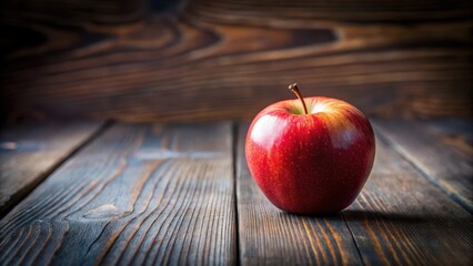 A single ripe red apple rests on a rustic wooden surface, bathed in warm, inviting light, creating a simple yet elegant still life scene.