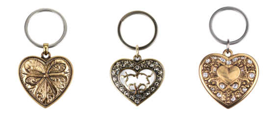 Three Heart Shaped Keychains In Gold Metal With Silver Rings Isolated On White Background Displaying Intricate Decorative Details