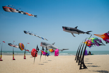 Flying kite festival with Octopus, jellyfish, shark fish and shaped animal. Various colorful kites flying in the blue sky on the public beach. Free public event featuring local of Thailand.