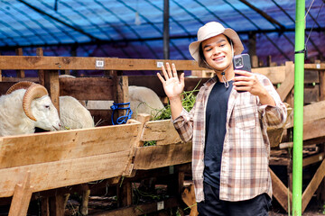 Young Asian Male Farmer Takes Selfie or Recording Video with Goats on Mobile Phone