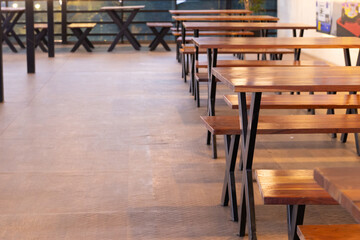 Beautifully arranged empty tables and stools arranged in a row before dining open in the evening in the restaurant