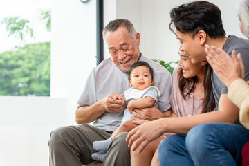 Portrait of Happy Asian Family at Home, Happy Grandparents, Parents, and Baby Bonding on Sofa, Multi-Generational Asian Family Smiling Together at Home