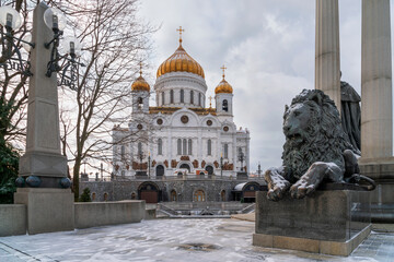 Cathedral of Christ the Savior on the background of a bronze sculpture of a lion at the foot of the monument to Alexander II the Liberator on a sunny winter day, Moscow, Russia