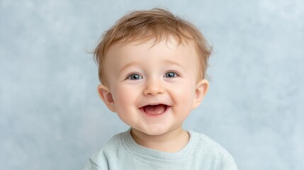 A joyful baby with bright blue eyes and a charming smile, radiating happiness against a soft blue background.