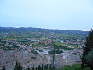 Fototapeta premium イタリア・グッビオの夕暮れ風景｜歴史ある街並みと丘陵に囲まれたウンブリア州の美しい眺め Evening view over historic Gubbio, Italy｜Panoramic landscape of medieval rooftops and Umbrian hills at dusk