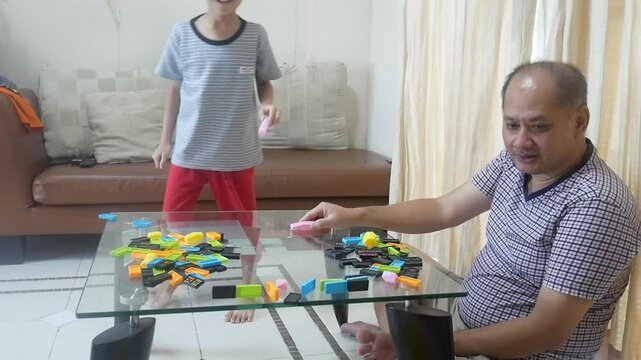 Father and son playing domino in the living room with happy 