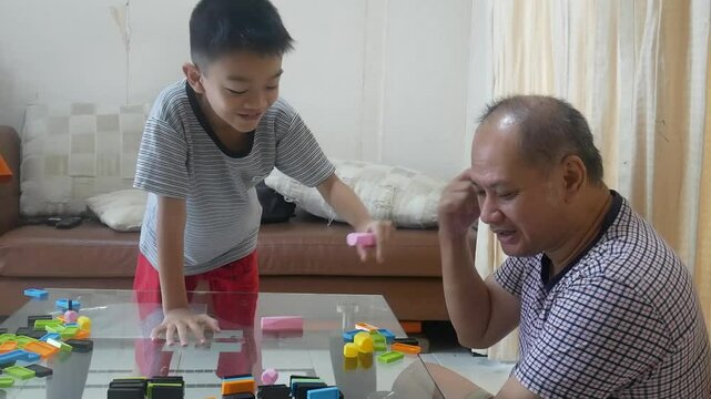 Father and son playing domino in the living room with happy 