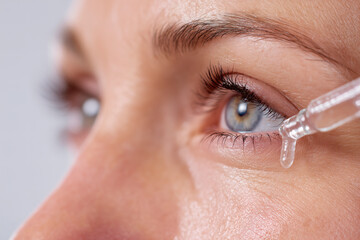 Eye care: Close-up of eye with dropper applying a liquid, suggesting hydration or eye treatment.