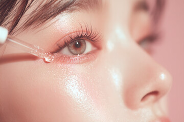Close-up of face applying eye serum; focusing on skincare and wellness with a delicate pink backdrop.