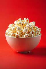 Close up of popped pop corn in bowl red background copy space