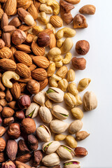 An assortment of various nuts, including almonds, cashews, pistachios, and hazelnuts on a white surface.