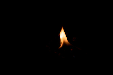 Close-up image of bright orange flames against a backdrop of black ash and burnt debris. A strong visual composition depicting the power, energy, and beauty of nature in the form of the fire element. 