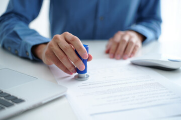 Close-up of a Person Stamping a Document at a Desk