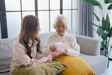 Obraz premium Young asian woman giving a gift to her Grandmother
