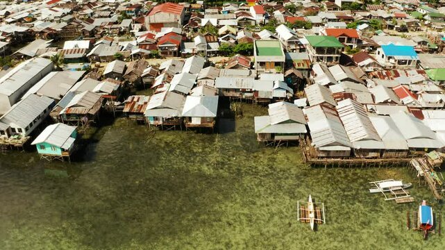 Old wooden house standing on the sea in the fishing village, aerial view. Dapa, Siargao, Philippines.