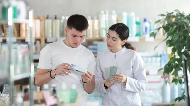 Man chooses ointment or gel in modern pharmacy. Female pharmacist helps with choosing a medicine. High quality 4k footage
