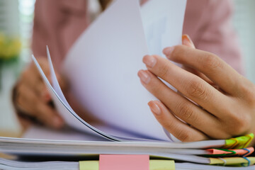A person's hands are busy organizing stacks of documents, marked with colorful paper clips and...