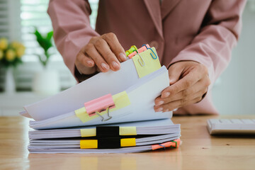 A person's hands are busy organizing stacks of documents, marked with colorful paper clips and...