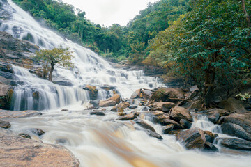 Beautiful waterfall with a lush green forest in the background. The water is flowing down the rocks and creating a beautiful scene. Sustainable waterfall in lush forest promoting water sustainability.