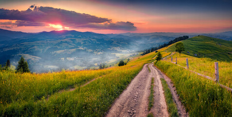 Astonishing morning scene of mountain valley with old country road, Zamagora village. Stunning summer sunrise in Carpathian mountains, Ukraine. Beauty of countryside concept background.