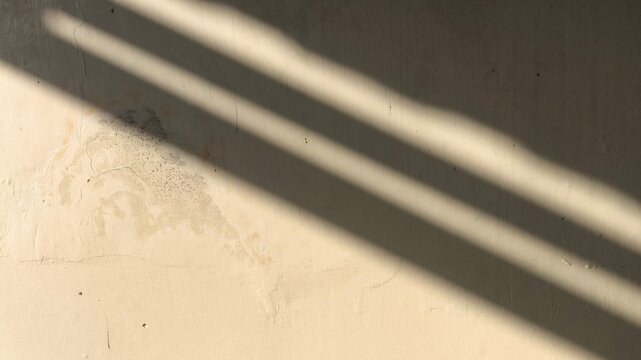 Old wall with textured surface and abstract window shadow overlay. Vintage inspired background for mockups, posters, minimalist scenes, or mood-driven design elements.
