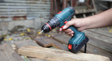 Impact Drill Machine : A close-up shot of a hand firmly gripping an electric drill a rough wooden...