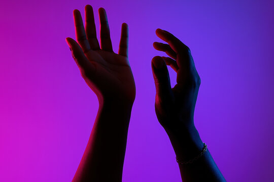 silhouetted hands reaching upward illuminated by vibrant purple and pink gradient lighting for creative modern concepts