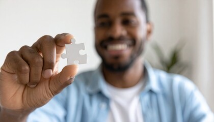 Smiling African American Man Holding Up a Single Puzzle Piece Showing Connection and Success in Business Strategy Problem Solving and Solutions for Teamwork