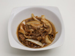 Stir fries meat and onion with sweet sauce on white plate
