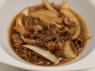 Stir fries meat and onion with sweet sauce on white plate