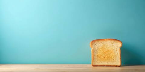 A single slice of toasted bread rests on a light wood surface against a tranquil teal backdrop