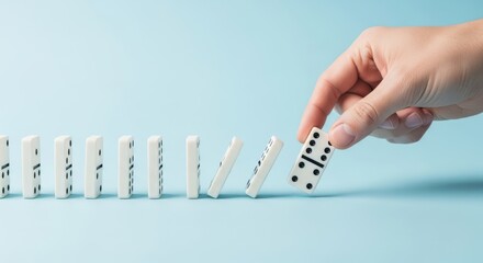 Fototapeta na wymiar Domino Effect Illustrated: A Captivating Hand Toppling a Series of White Dominoes on a Light Blue Background