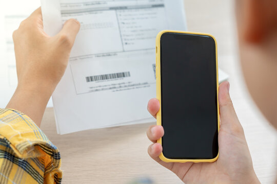 woman use phone scan barcode or QR codes to pay credit card bill after receiving document invoice. payment, receive, paying electricity, digital payments, technology, scanning, financial transactions