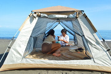 Seated inside the tent, a teenage girl watches as her friend steps out to pick up supplies from the...